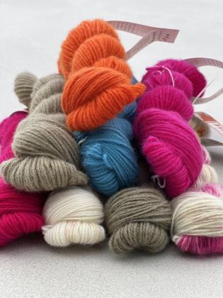 Mehrere 25-g-Cashmere-Stränge (No. 94) in kräftigem Pink, Neonorange, Türkis, Naturweiß mit zarten Sprenkeln und Taupe – als Inspirationsbeispiele für Wunschfärbungen.
